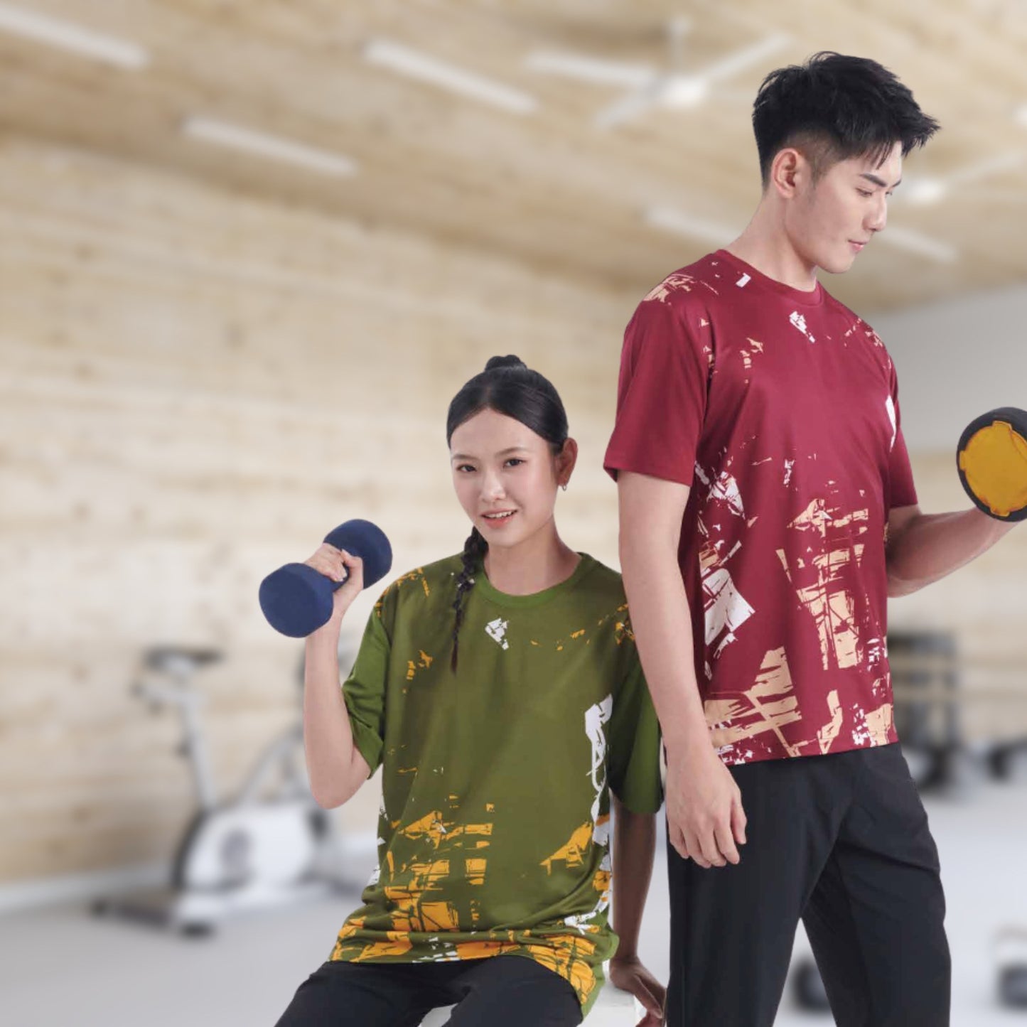 Two models wearing the QD91 unisex sublimation mini eyelet t-shirt in maroon and olive at a gym, showing the all-over printed design